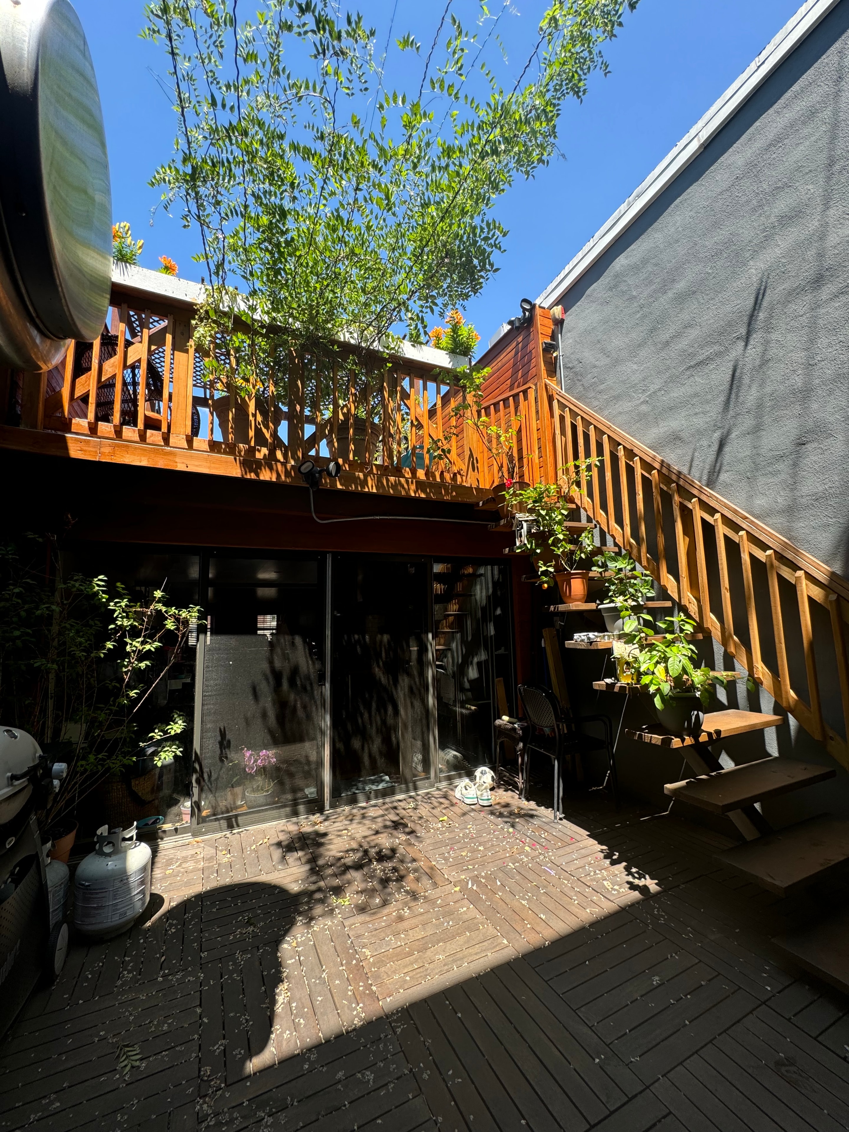 1st floor roof deck with wooden pergola, planters, and brick patio